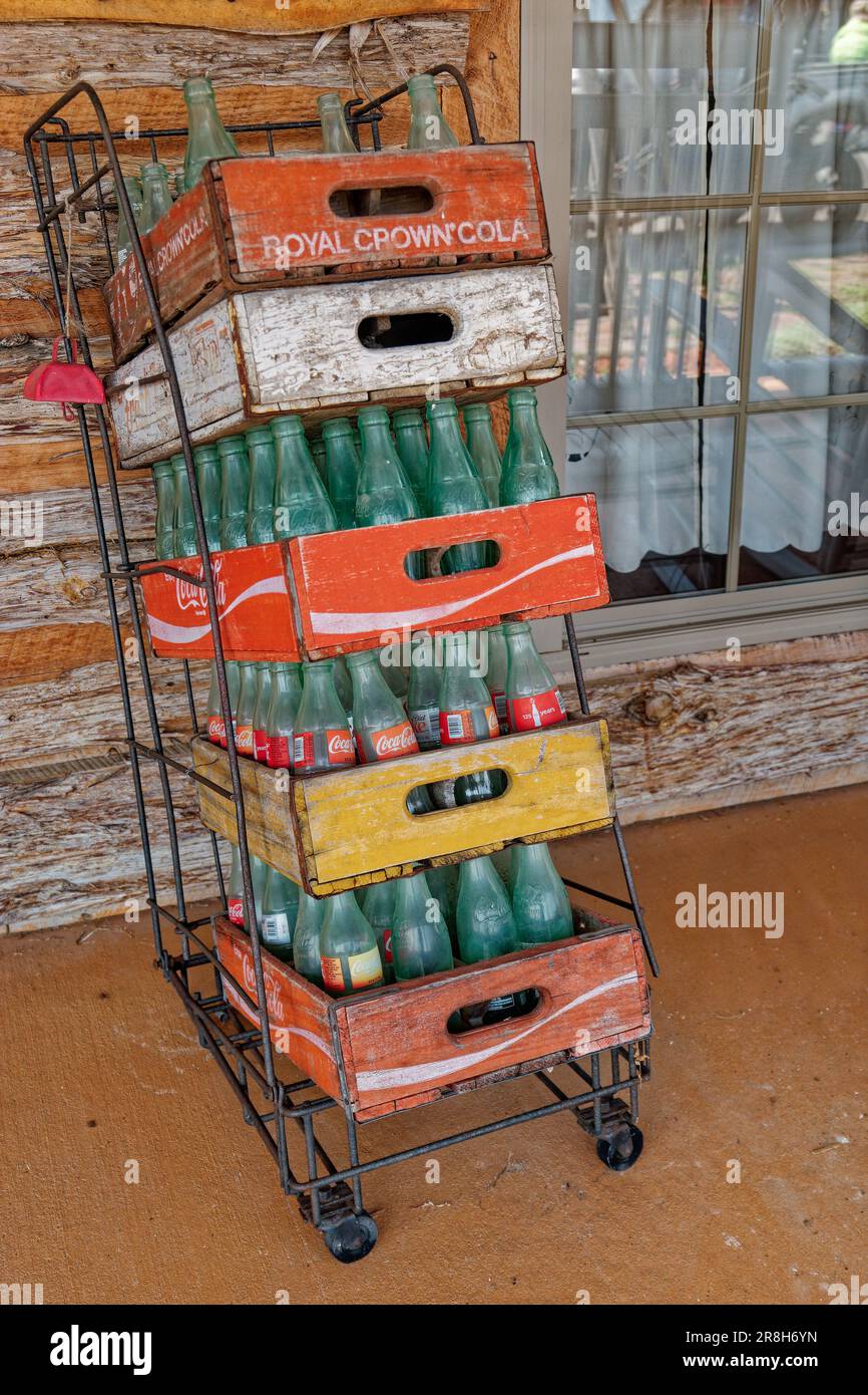 Plusieurs bouteilles de Coca-Cola vides dans des caisses de soda en bois d'époque empilées verticalement dans un support en fil métallique contre un bâtiment à l'extérieur vue rapprochée Banque D'Images