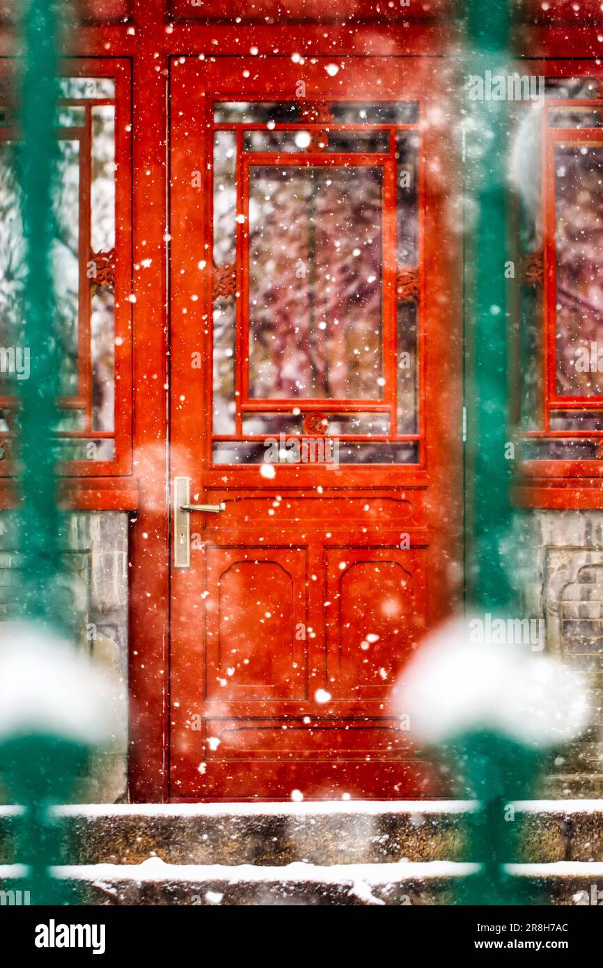 Une porte en bois rouge est fermée dans le paysage d'hiver, créant une image saisissante de beauté et de sérénité Banque D'Images