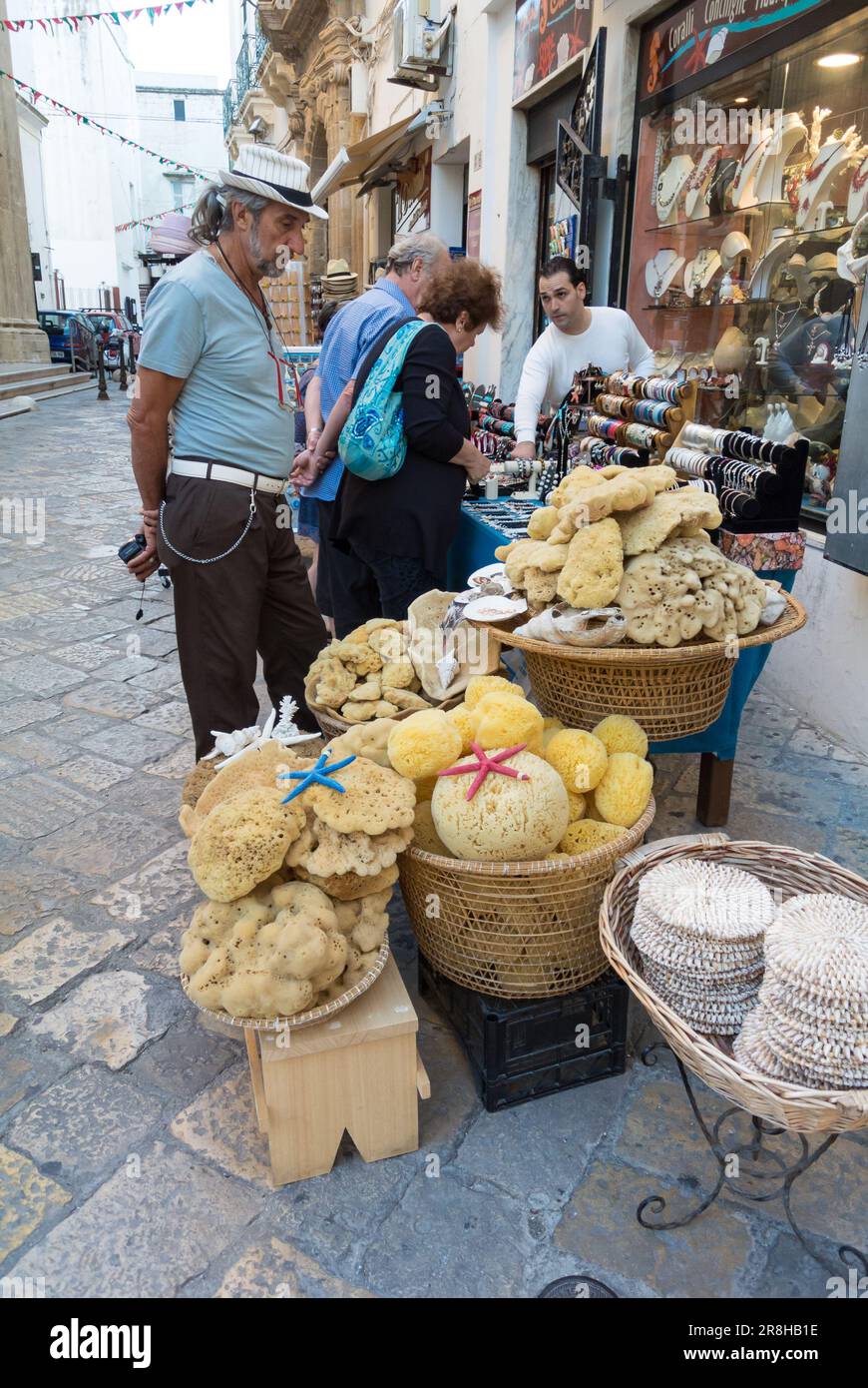 Gallipoli, province de Lecce, Italie, touristes à un stand avec des éponges de mer dans la rue de Gallipoli Banque D'Images
