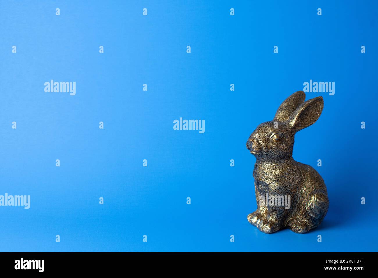 Figurine de lapin doré sur fond bleu. Espace libre Banque D'Images