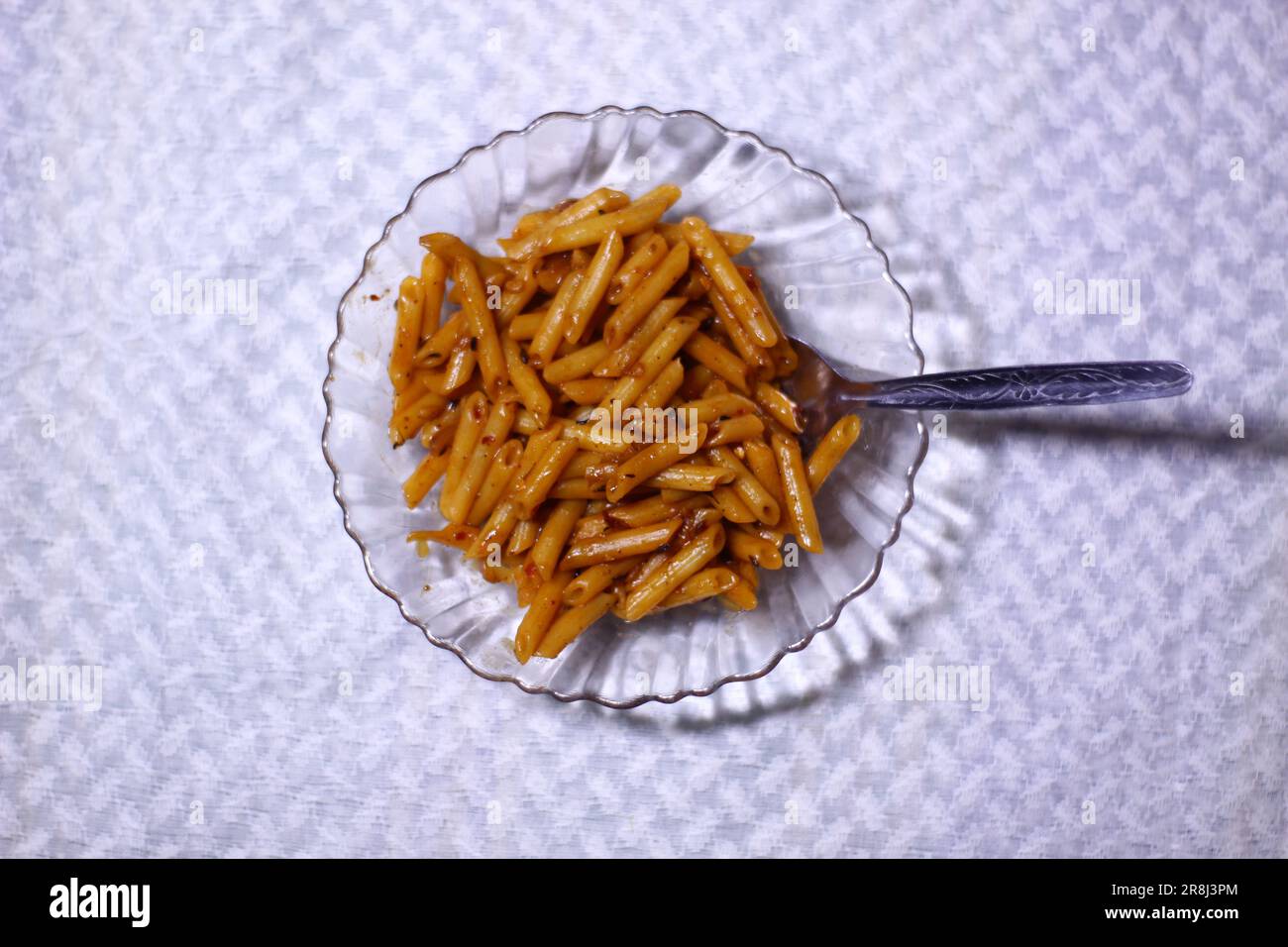 Vue en grand angle des pâtes délicieuses dans un bol en verre avec une cuillère isolée sur fond blanc texturé espace négatif pour écrire du texte Banque D'Images