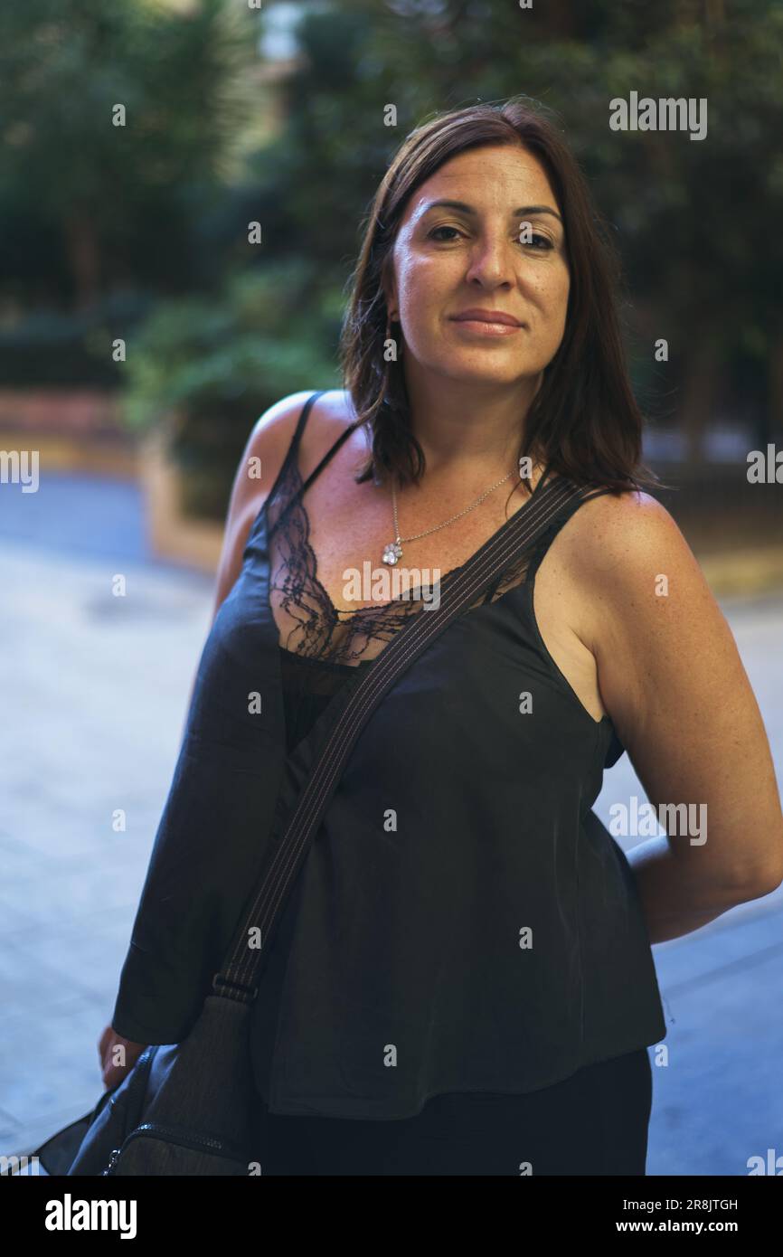 Portrait énigmatique d'une femme brune en plein air, avec un fond d'arbres flous qui ajoute de la profondeur et du mystère à l'image Banque D'Images