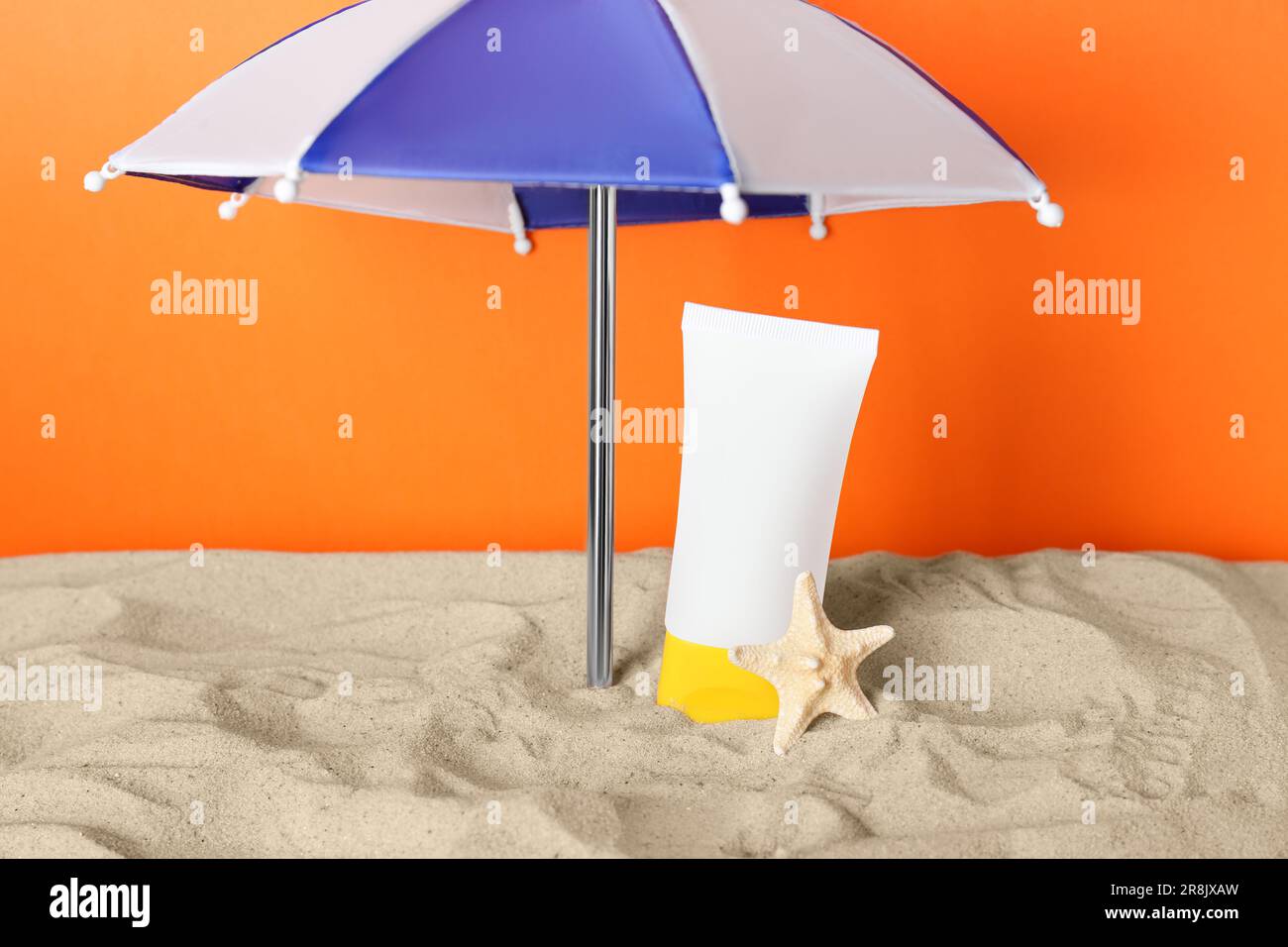 Produit de bronzage et étoiles de mer sous un parasol sur du sable sur fond  orange Photo Stock - Alamy