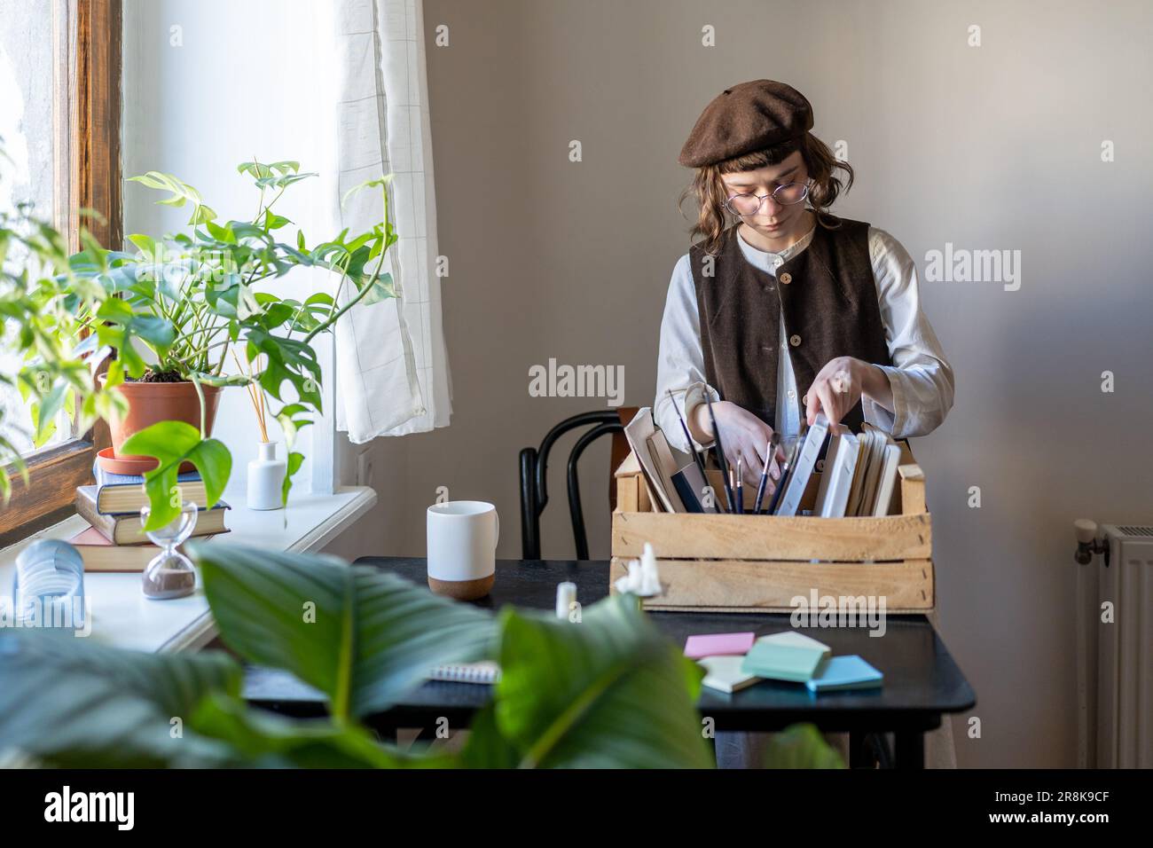 Creative hipster fille portant beret organisant des outils d'art et des matériaux de peinture Banque D'Images