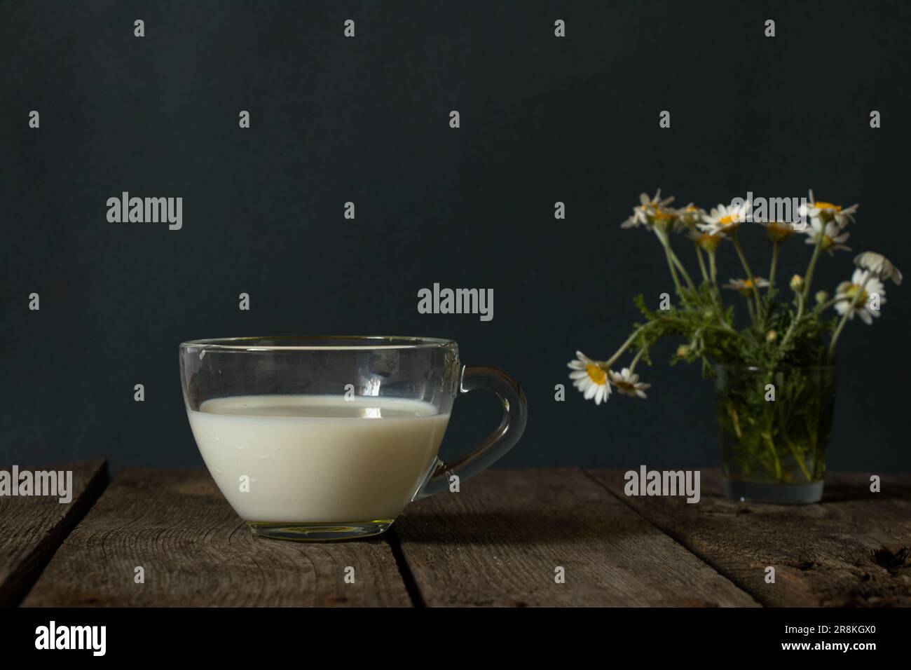 verre de lait et de pâquerettes sauvages sur une table le matin Banque D'Images