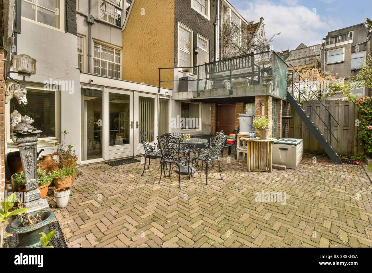 une cour arrière avec meubles de patio et salle à manger extérieure sur un sol en briques parcourus en face de la maison Banque D'Images
