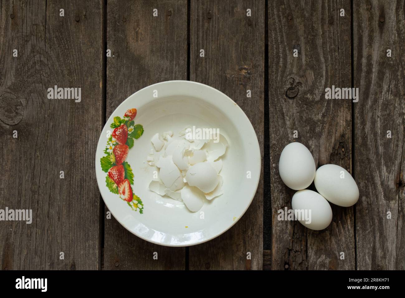 coquille d'œuf dans des assiettes et près des œufs sur une table en bois Banque D'Images