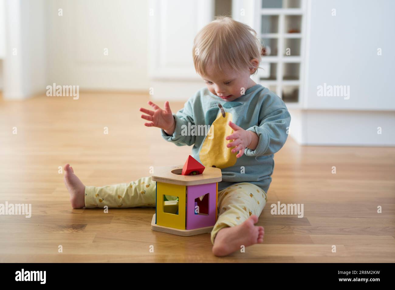 Tout-petit avec le syndrome de Down jouant avec le trieur de forme Banque D'Images