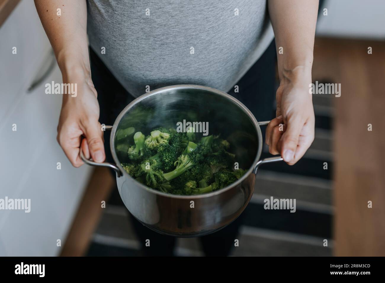 Mains de femme tenant une casserole avec le brocoli bouilli Banque D'Images