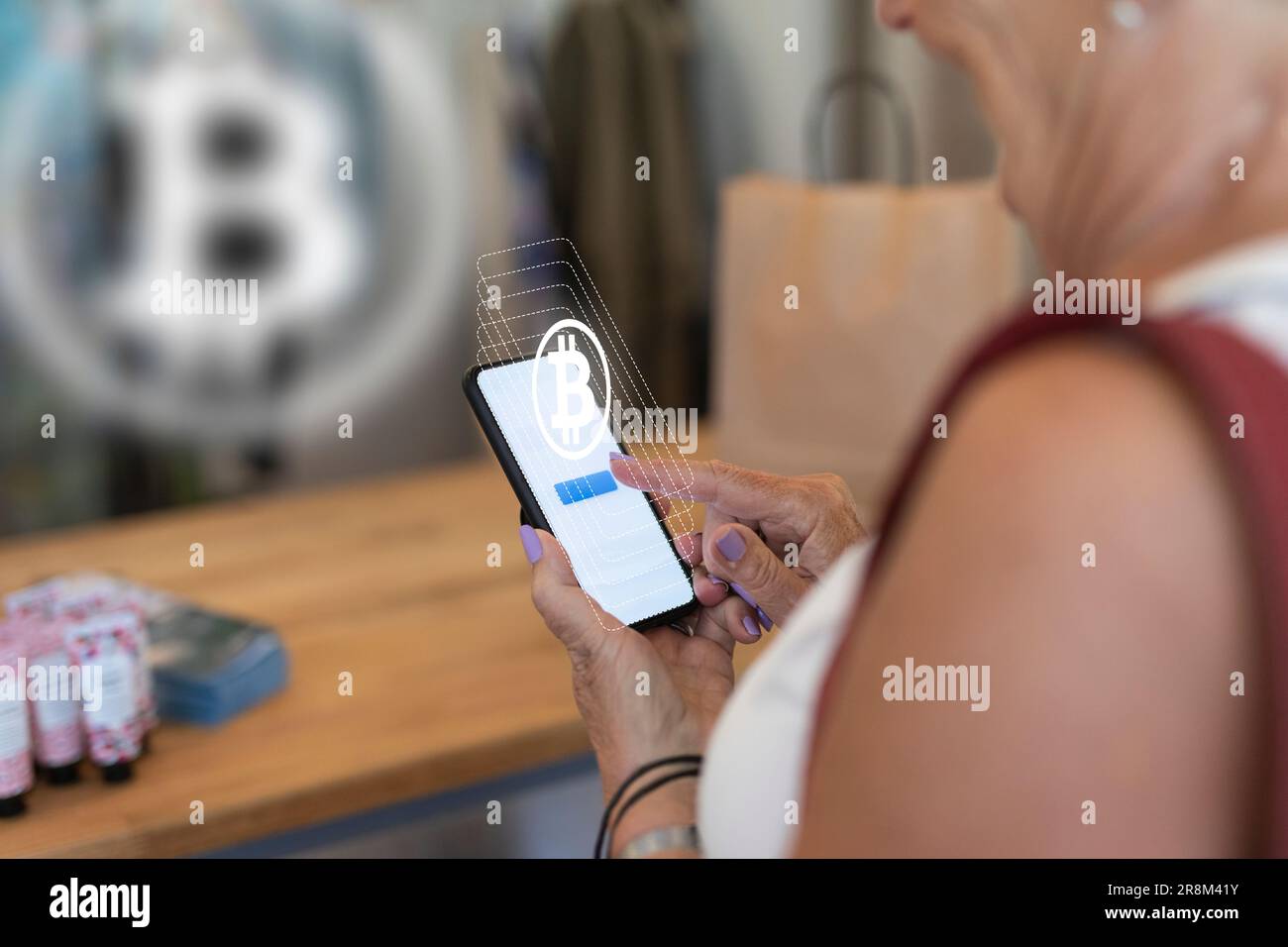 Femme payant avec la monnaie de crypto bitcoin en magasin Banque D'Images