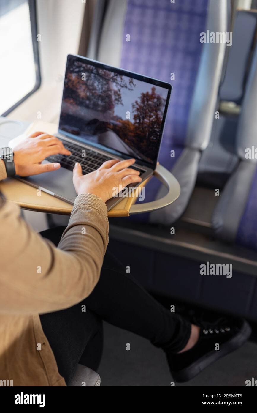 Section moyenne d'une femme utilisant un ordinateur portable pendant le voyage en train Banque D'Images