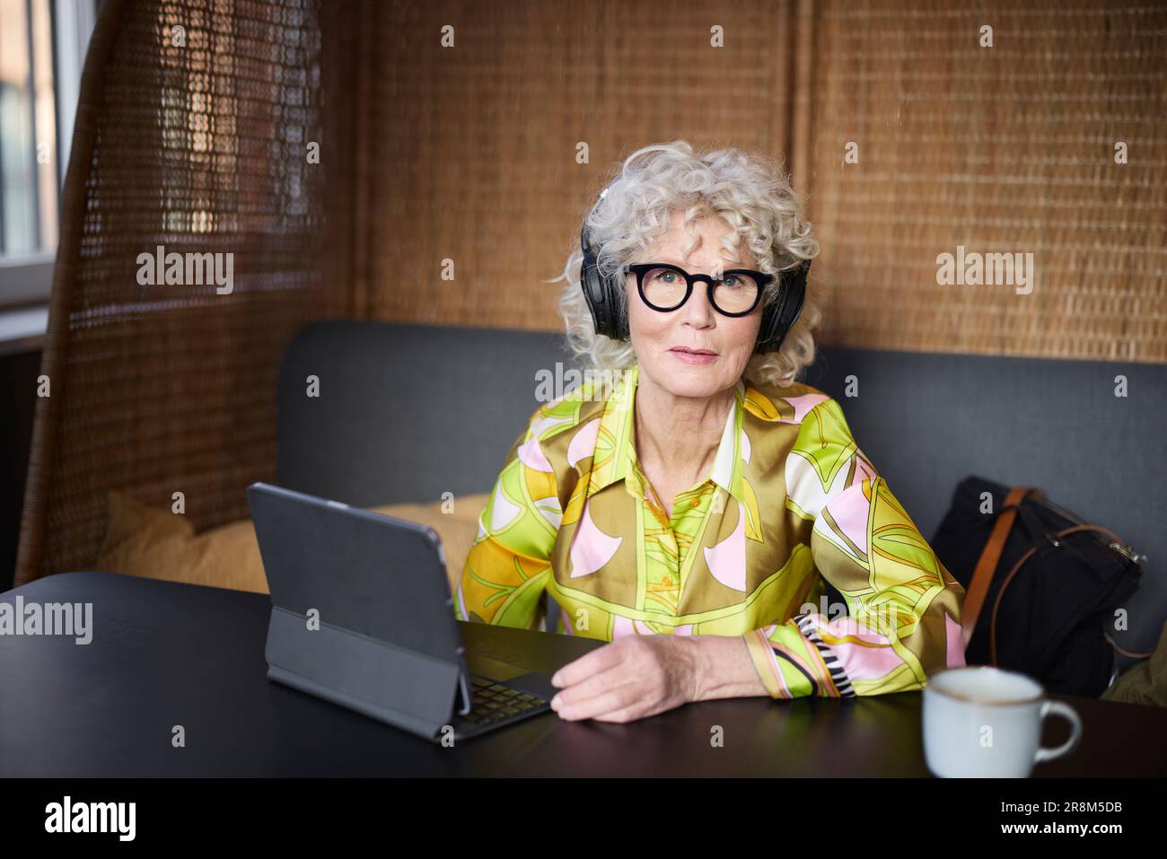 Portrait d'une femme âgée avec un casque à l'aide d'une tablette Banque D'Images
