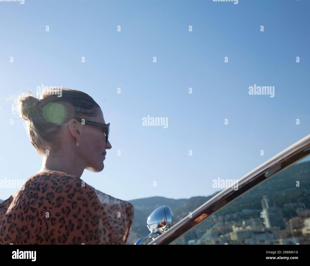 Femme en lunettes de soleil regardant vers l'avant tout en conduisant le bateau, flair d'objectif Banque D'Images