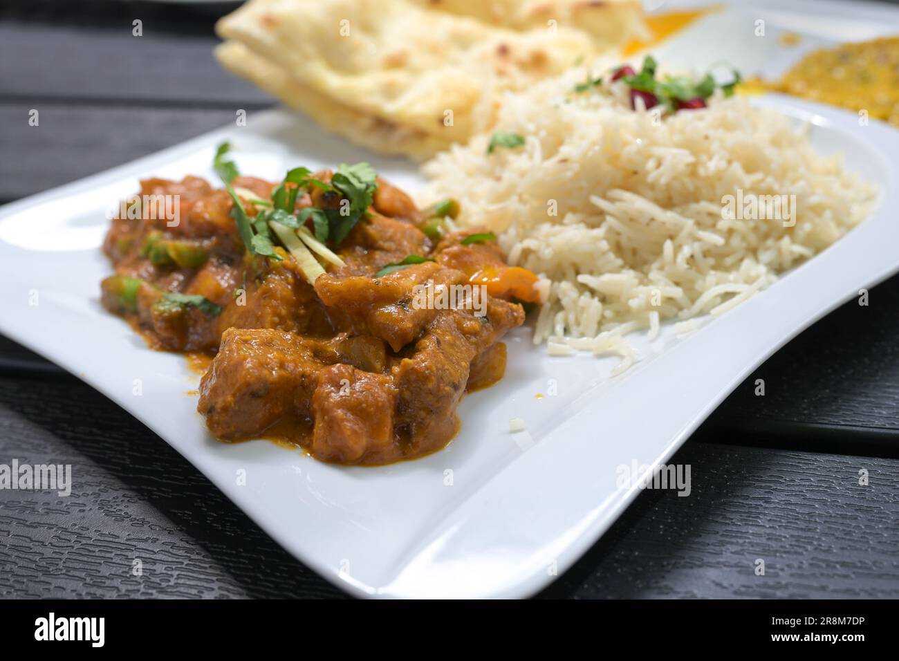 Repas indien, bœuf aux légumes dans une sauce épicée, riz et pain sur une assiette blanche et une table noire, foyer choisi, profondeur de champ étroite Banque D'Images