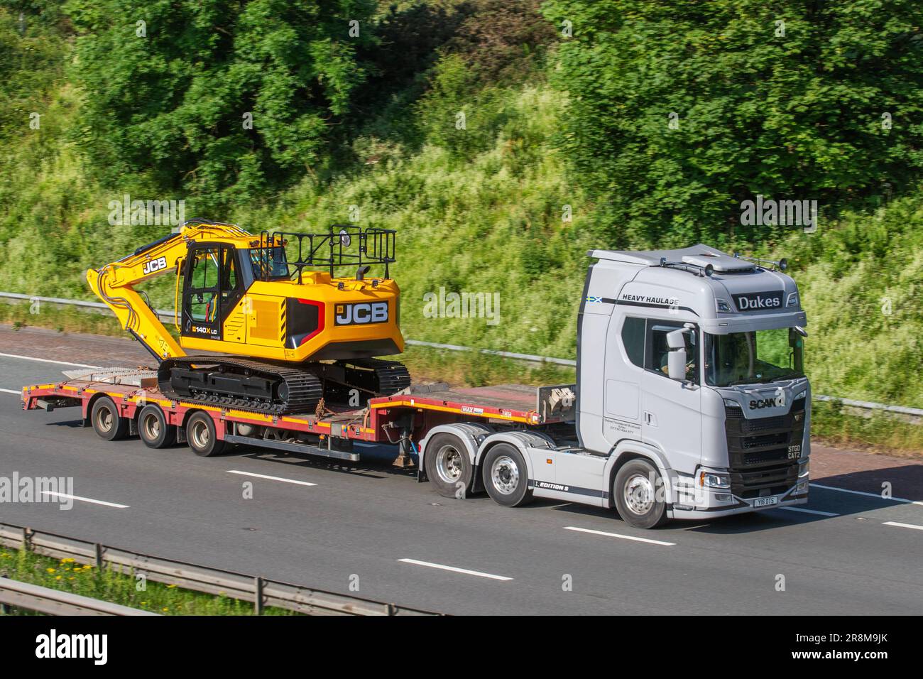 CAMION DUKES Heavy Haulage HGV Scania transportant une pelle hydraulique à chenilles JCB 140X sur une remorque à châssis pas ; se déplaçant sur l'autoroute M6 dans le grand Manchester, Royaume-Uni Banque D'Images