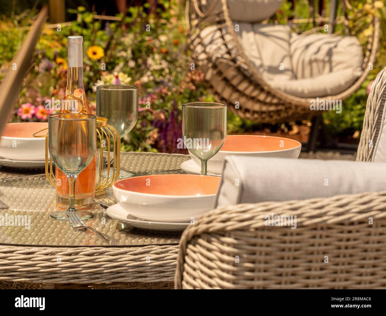 Table de jardin extérieure pour le dîner avec fauteuil à œufs en rotin au loin. Banque D'Images