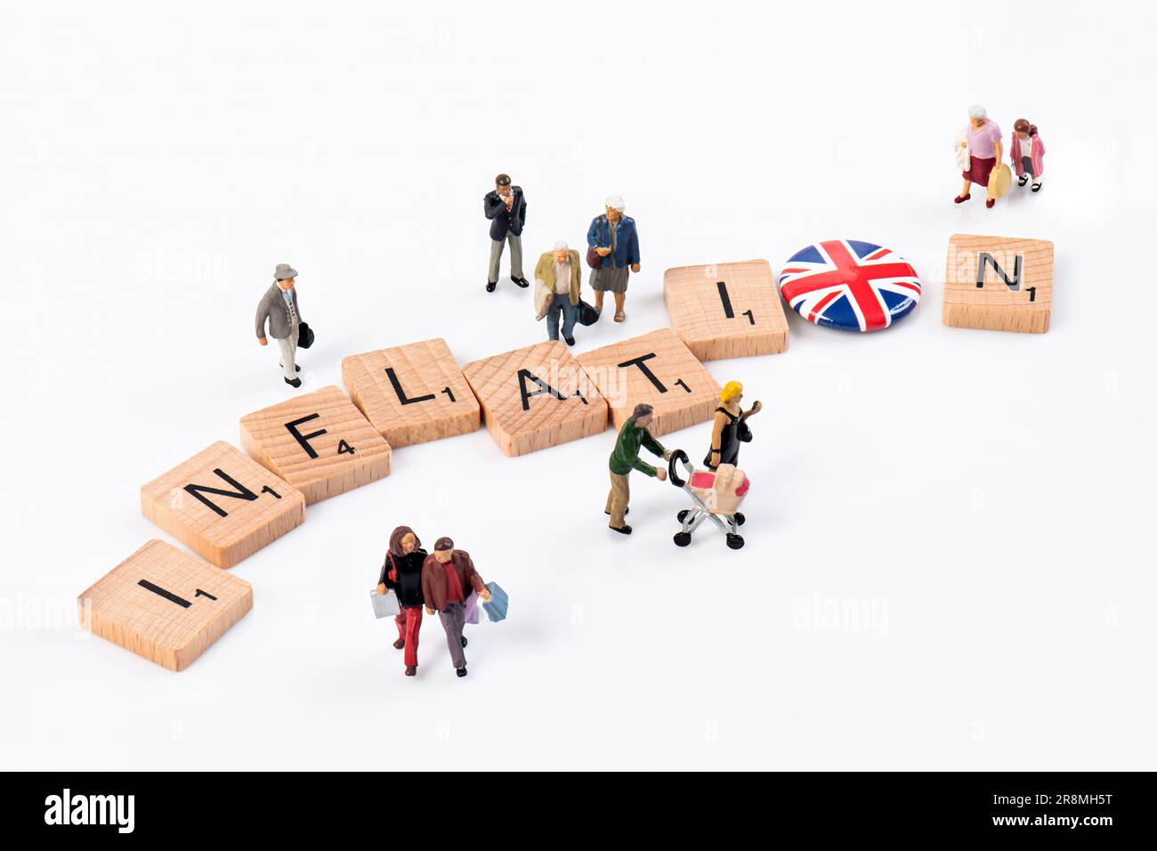 Inflation- des lettres en bois Scrabble disposées pour épeler 'inflation' entouré de petites figurines représentant divers groupes d'âge. Banque D'Images