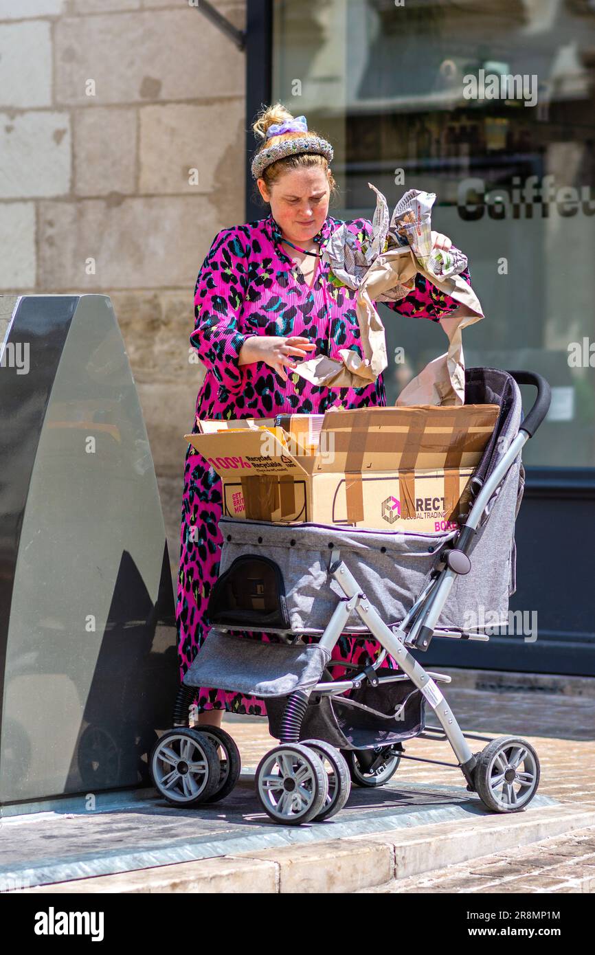 Femme en surpoids dans une grenouille bizarre de jeter des déchets de papier de poussette de bébé dans le distributeur de conseil en centre-ville - Tours, Indre-et-Loire (37), France. Banque D'Images