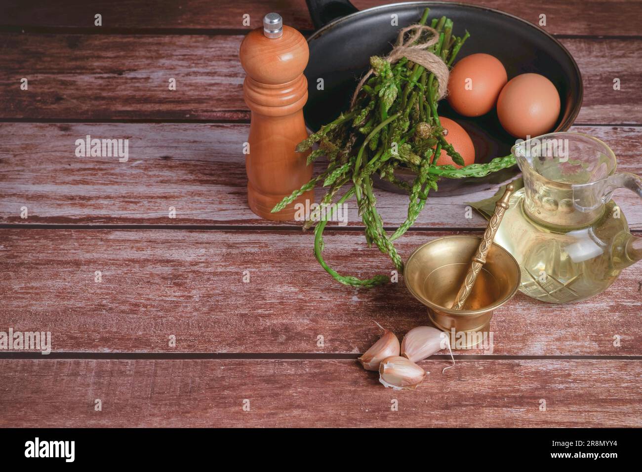 Bouquet d'asperges sauvages dans une poêle avec œufs, ail, huile d'olive et poivre, ingrédients pour faire une omelette Banque D'Images