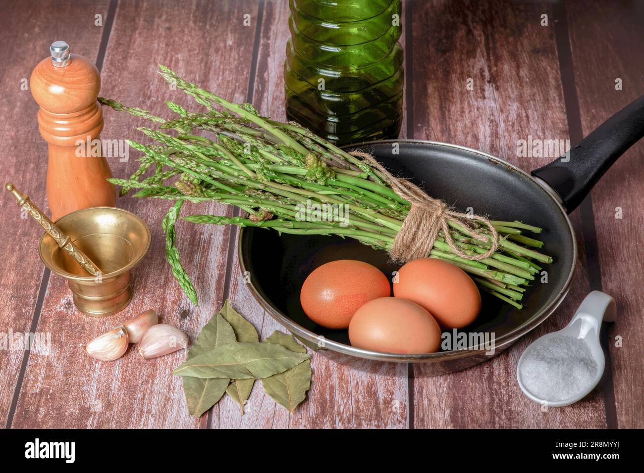 Bouquet d'asperges sauvages dans une poêle avec œufs, ail, huile d'olive et poivre, ingrédients pour faire une omelette Banque D'Images