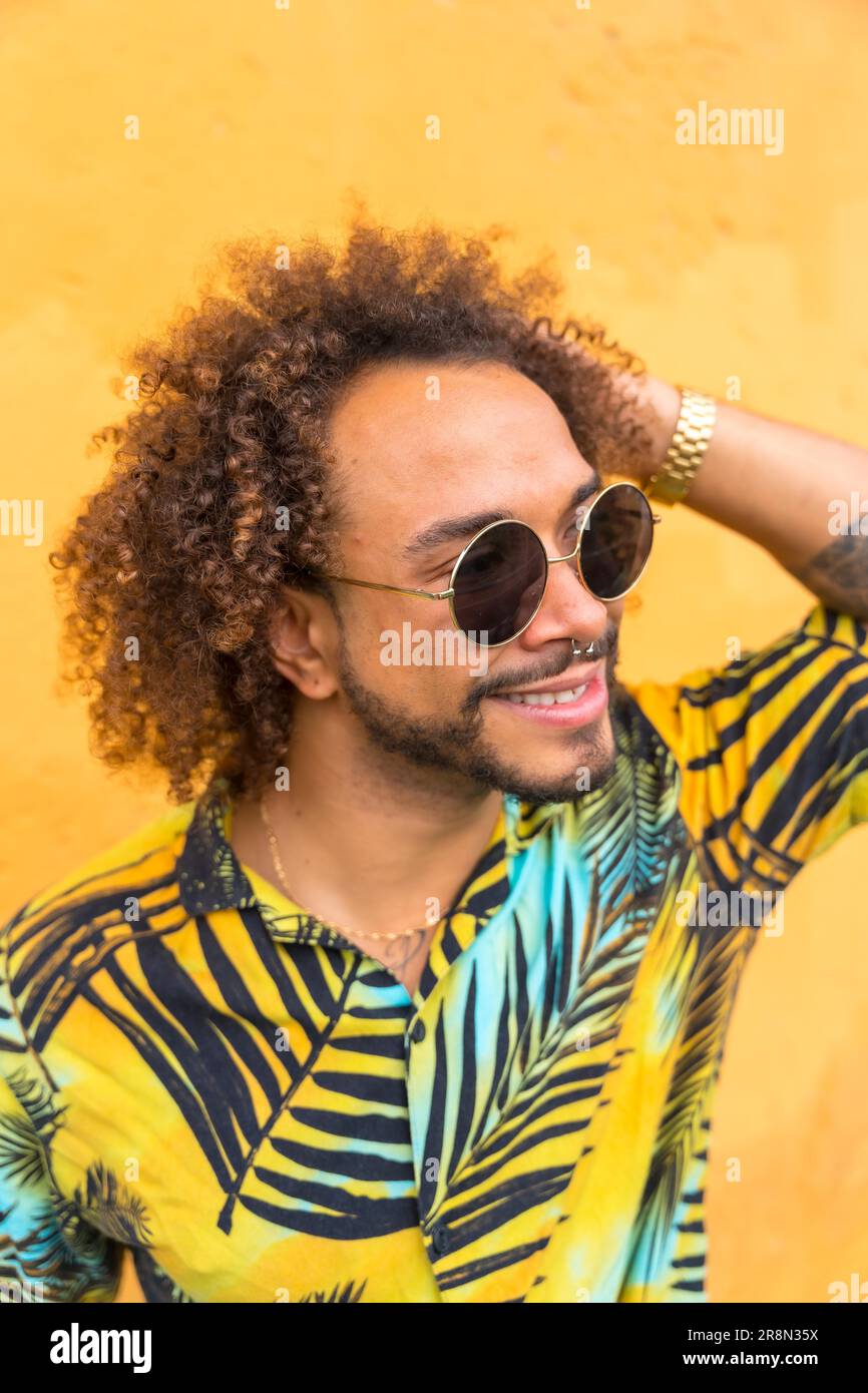 Portrait d'un homme attrayant avec des cheveux afro en été dans une chemise de palmier sur fond jaune Banque D'Images