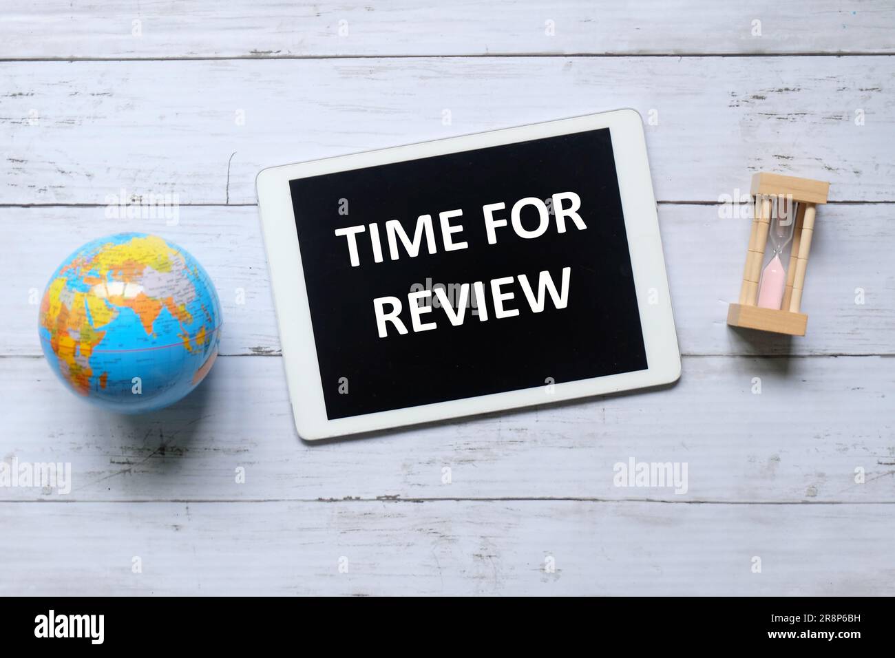 Vue de dessus du globe, de l'horloge de sable et de la tablette écrit avec le temps pour la revue sur fond de bois. Banque D'Images