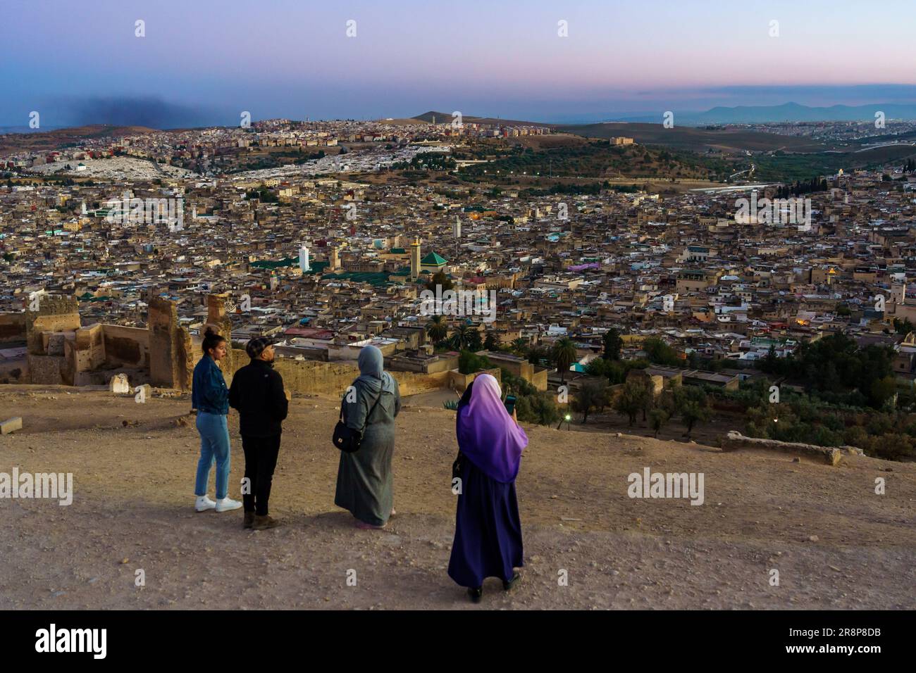 Maroc. Fez. Personnes sur la colline au-dessus de la vieille médina à Fès au crépuscule. Au centre de la mosquée Karaouiyine Banque D'Images