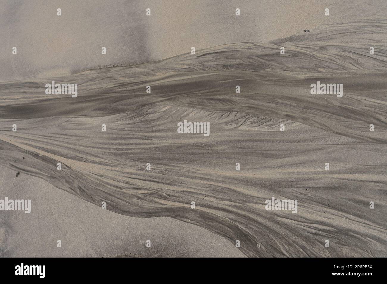 Une surface de sable brun grisâtre avec des lignes abstraites. Banque D'Images