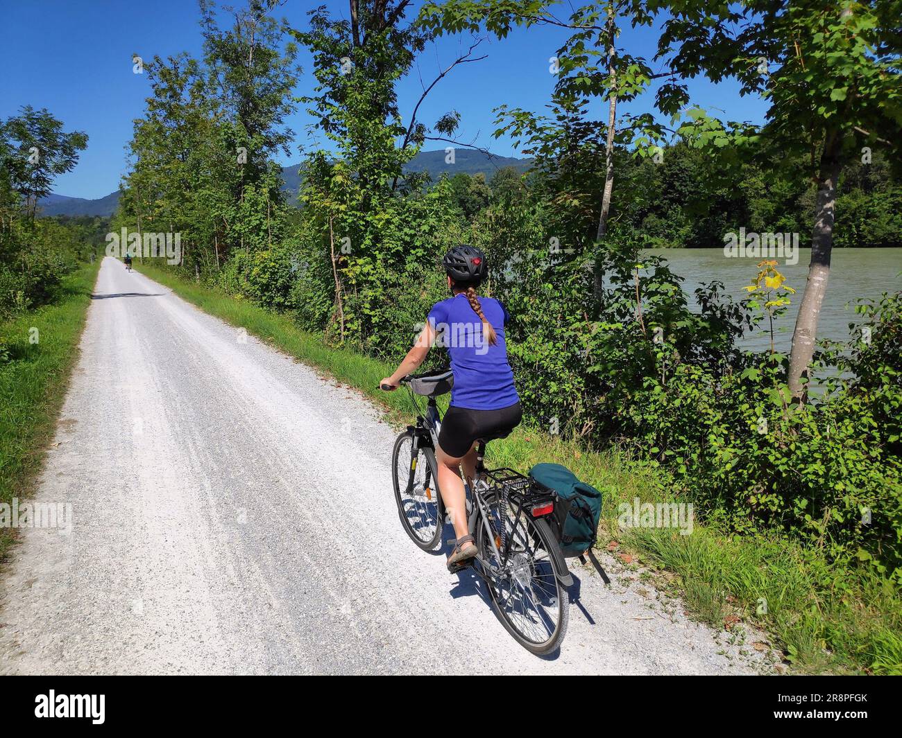 Une cycliste qui porte un casque se déplace le long de la rivière Salzach près de Salzbourg sur la piste cyclable longue distance Tauernradweg en Autriche. Banque D'Images