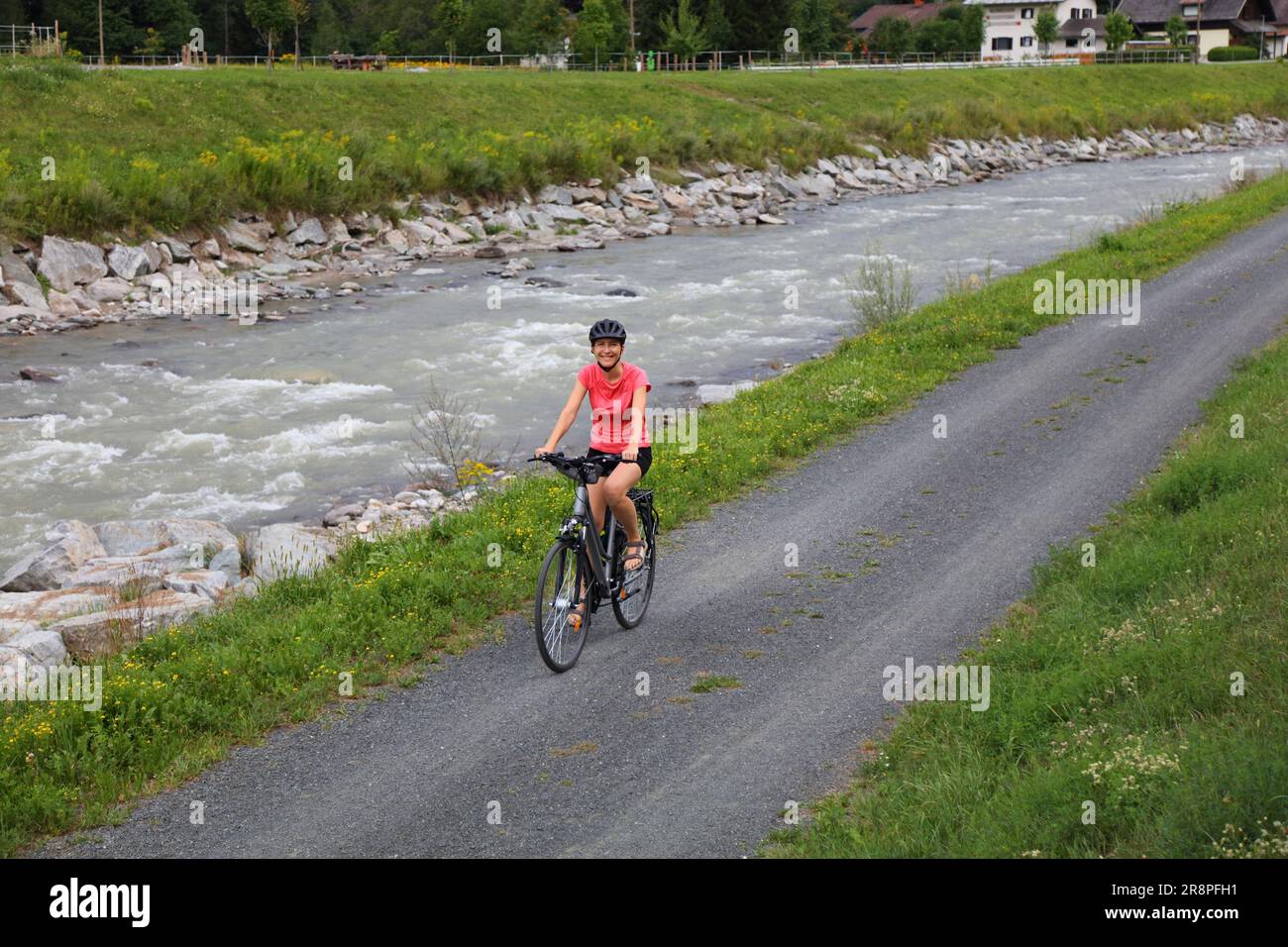 Cycliste femelle dans le ridin du casque sur la piste cyclable longue distance de Gailradweg dans la région de Gailtal en Carinthie, Autriche. Banque D'Images