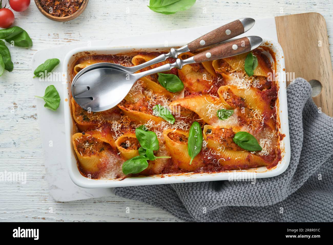 Cannelloni ou conchiglioni. Pâtes farcies cuites à la sauce à la viande bolognaise, tomates, basilic sur une table en bois blanc rustique. Bo traditionnel italien Banque D'Images