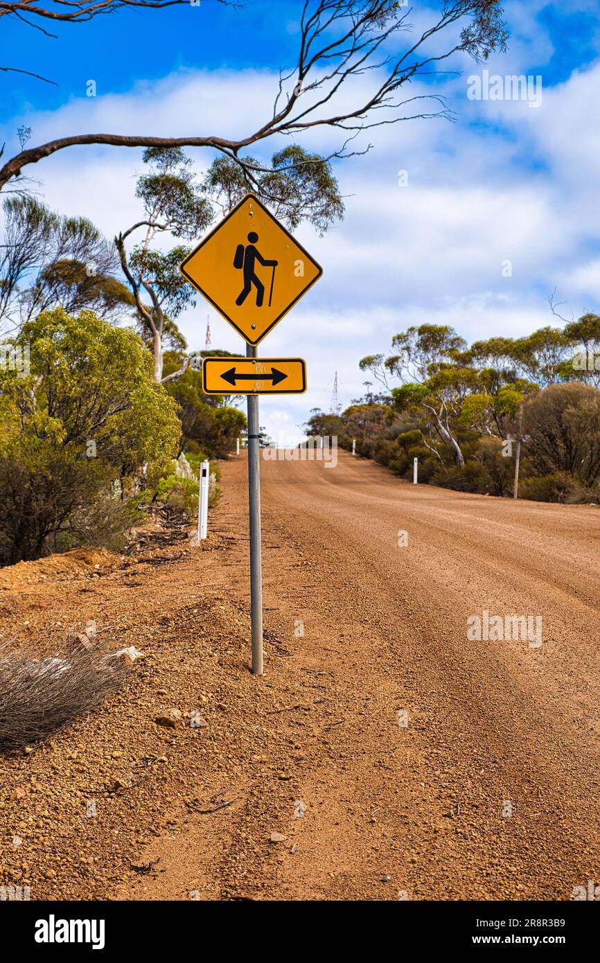Panneau d'avertissement le long d'une route de gravier dans l'Outback australien : le sentier de randonnée traverse la route. Banque D'Images