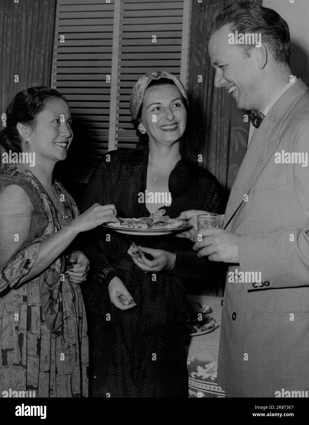 À gauche : Mme. A.J. Agbayani, dont le mari est l'officier du service extérieur de la Ligue des Philippines, Mme M. Brenner, et le vice-consul du Danemark, M. E. Trolle-Hansen, au parti de M. et Mme Nurock. M. Trolle-Hansen partira sous peu pour la Nouvelle-Zélande pour devenir la charge d'affaires danoise. 16 mars 1955. Banque D'Images