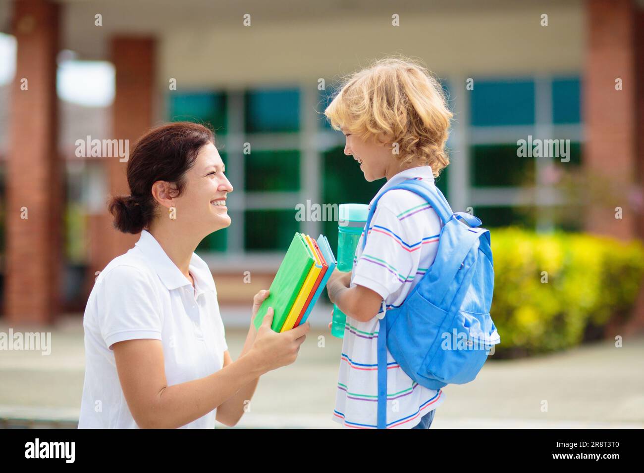 Mère amenant l'enfant à l'école. Les parents viennent chercher un petit garçon après le cours. Jeune maman qui prend un enfant après des leçons de maternelle ou d'école maternelle. Banque D'Images