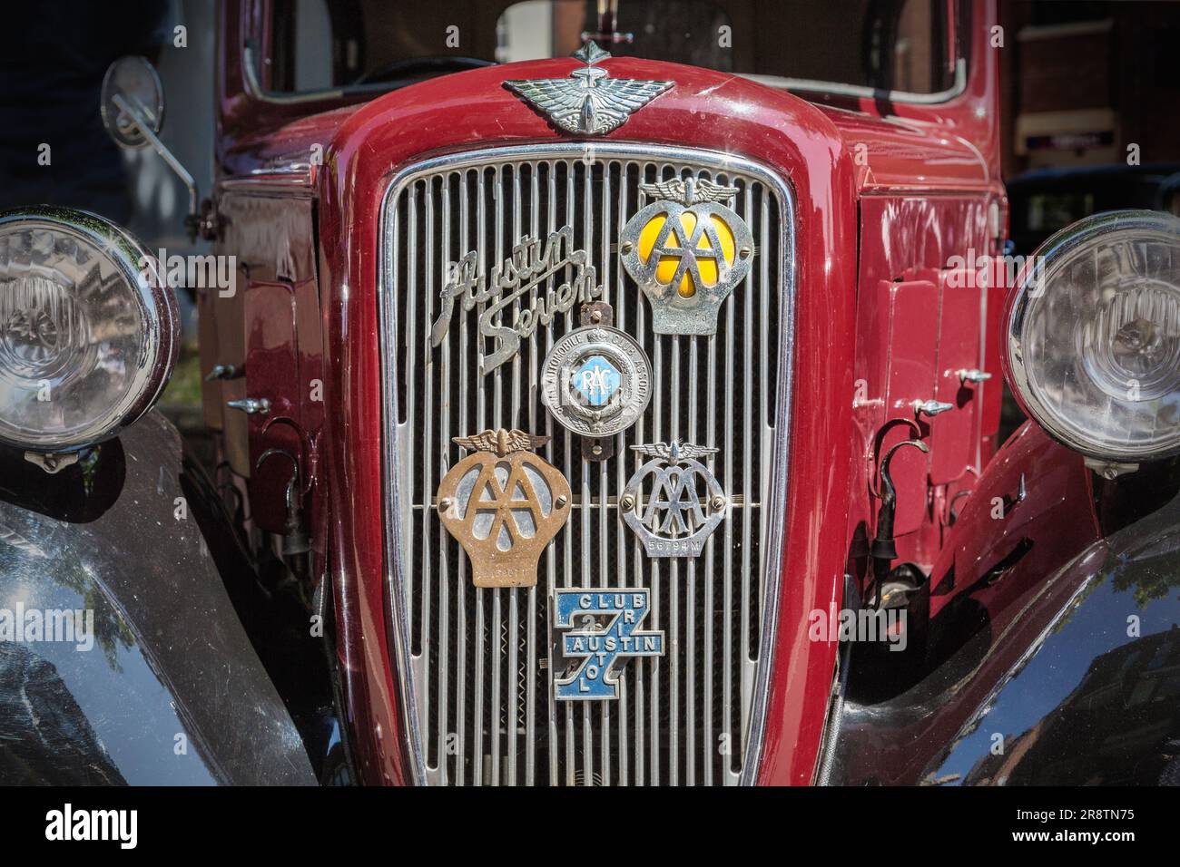 Vue de face détaillée d'une Austin Seven rouge des années 1930 avec divers badges motorisés sur la calandre. Austin Ruby à un salon de voitures classiques et vintage. Banque D'Images