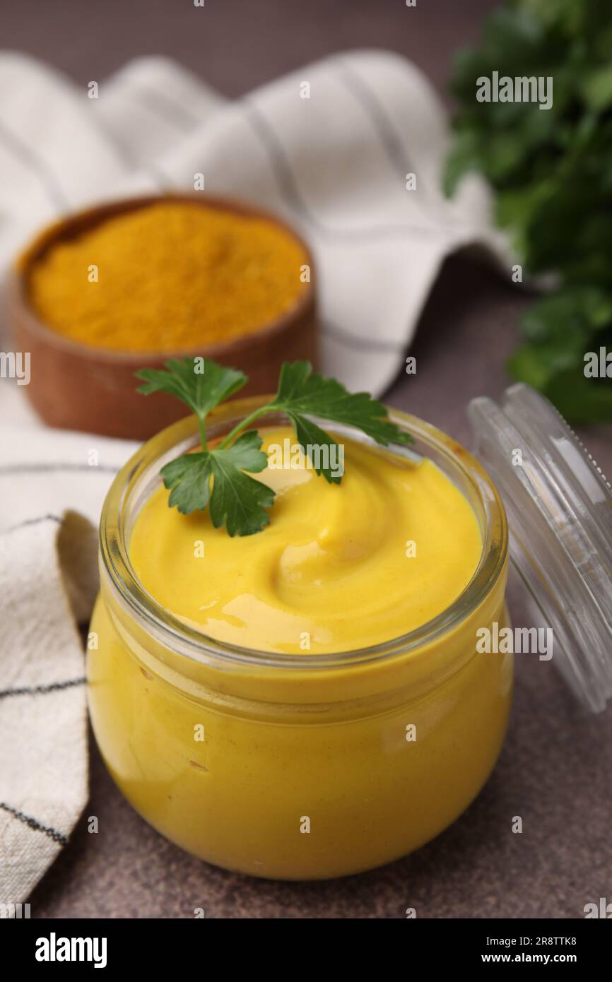 Jarre avec une savoureuse sauce au curry, de la poudre et du persil sur une table brune Banque D'Images