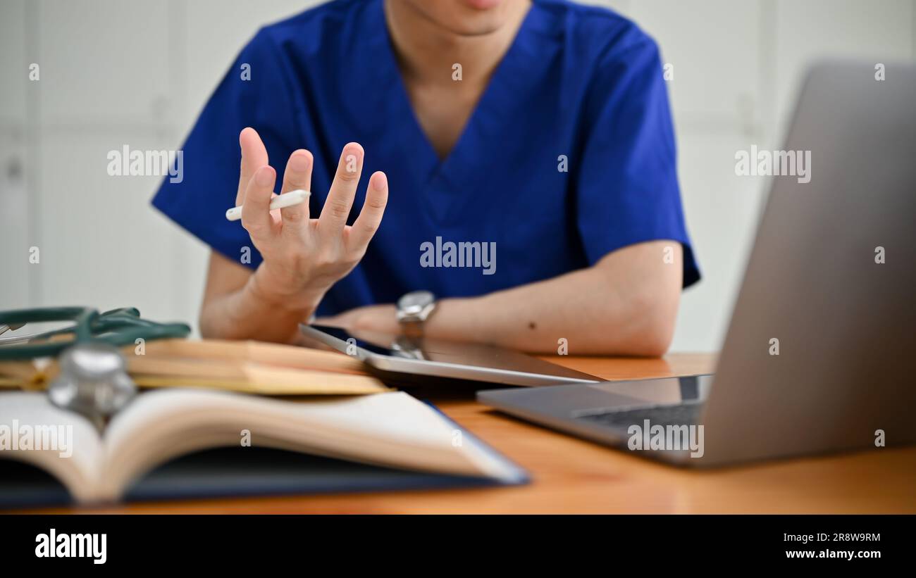 L'image rapprochée d'un étudiant ou d'un médecin spécialisé en médecine masculine dans les exfoliations est d'avoir un examen médical en ligne avec un patient ou de se joindre à un webi médical Banque D'Images