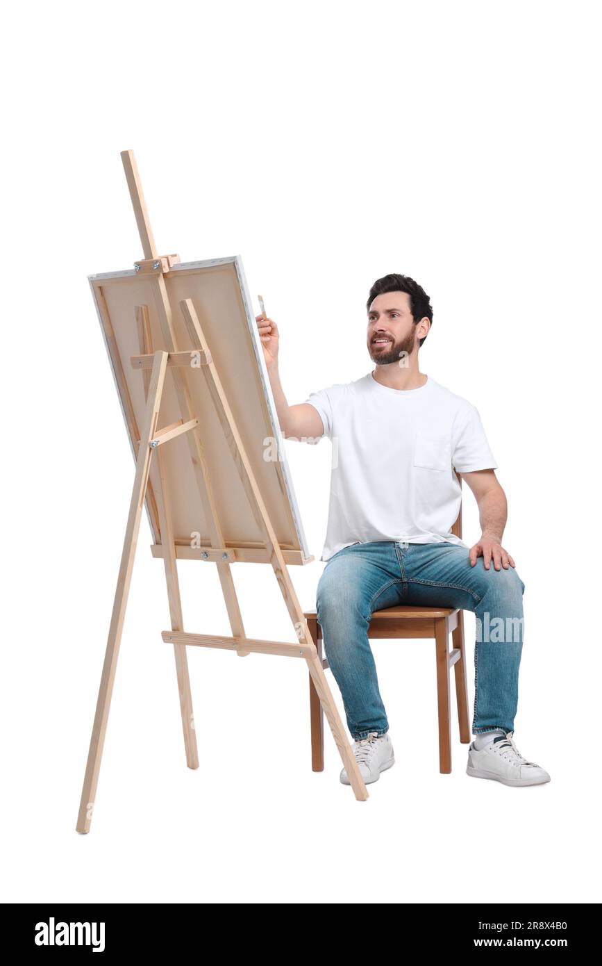 Homme peignant avec un pinceau sur fond blanc. Utilisation du chevalet pour tenir la toile Banque D'Images
