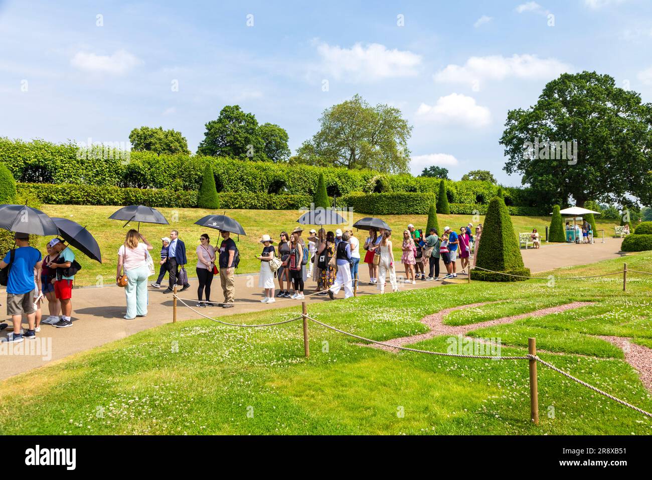 Les touristes avec parasols pendant une chaude journée d'été attendent dans la file d'attente au Palais de Kensington, Londres, Angleterre, Royaume-Uni Banque D'Images