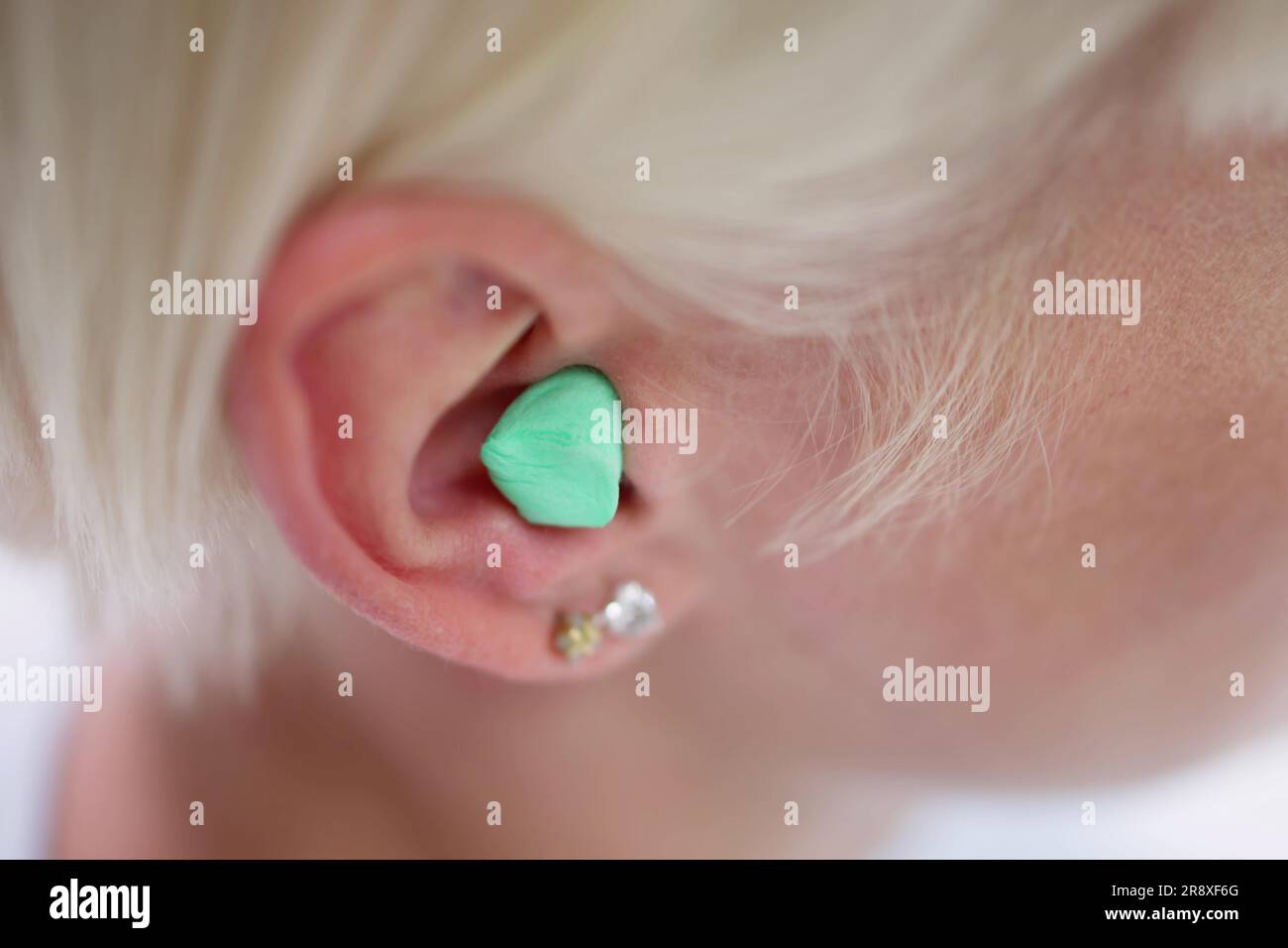 Femme mettant le bouchon d'oreille dans son oreille dans le lit Banque D'Images