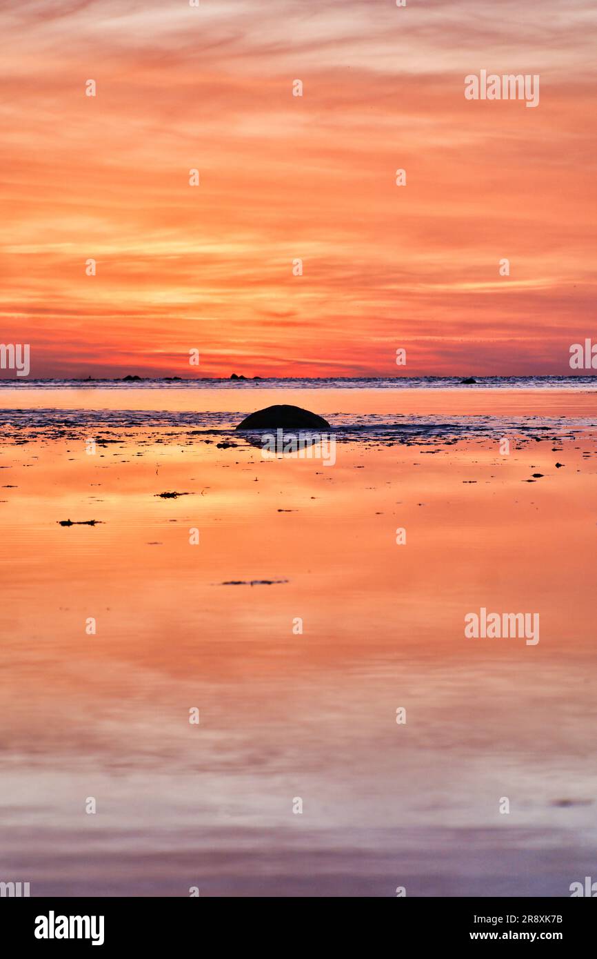 Coucher de soleil, petit rocher à marée basse devant la mer illuminée. Ondes lumineuses. Île de Poel sur la mer Baltique. Photo de la nature de la côte Banque D'Images