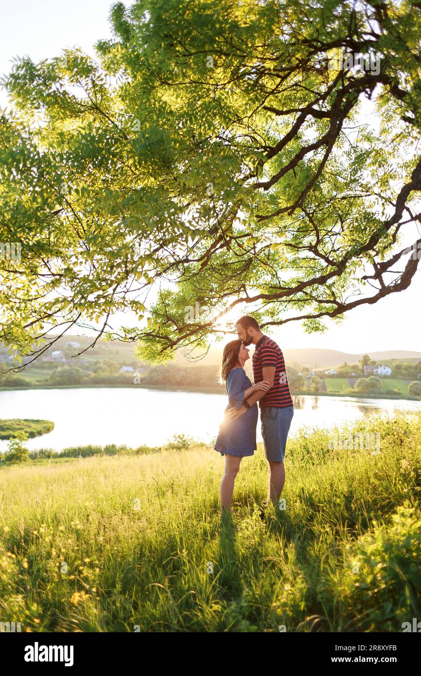 l'homme et la femme s'embrassent dans le champ de fleurs aux rayons du soleil Banque D'Images