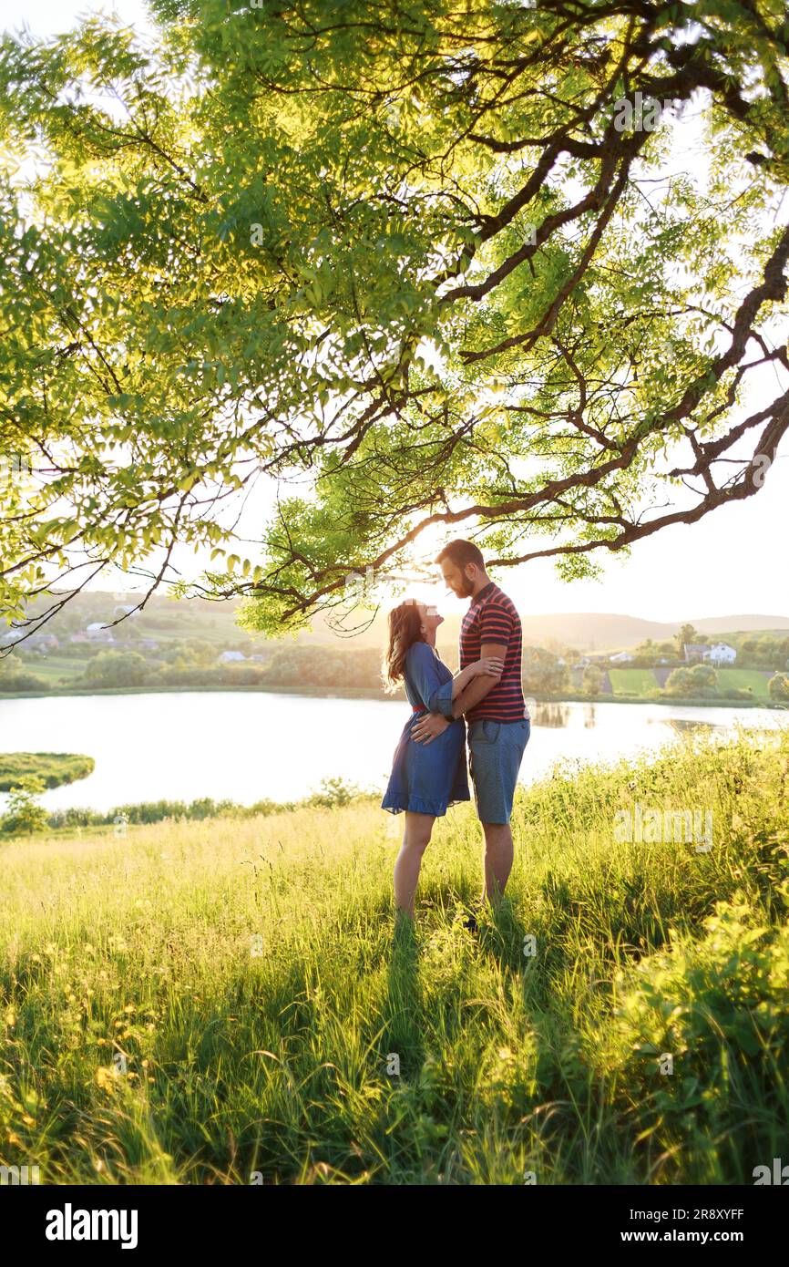 l'homme et la femme s'embrassent dans le champ de fleurs aux rayons du soleil Banque D'Images