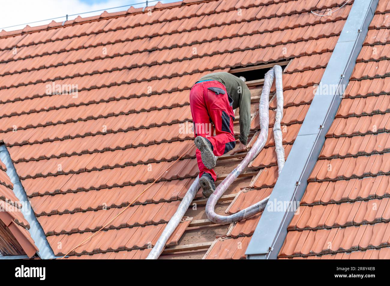 artisan sur les escaliers, soufflage de l'isolation de toit en mousse, application à l'aide d'un tuyau sous pression Banque D'Images