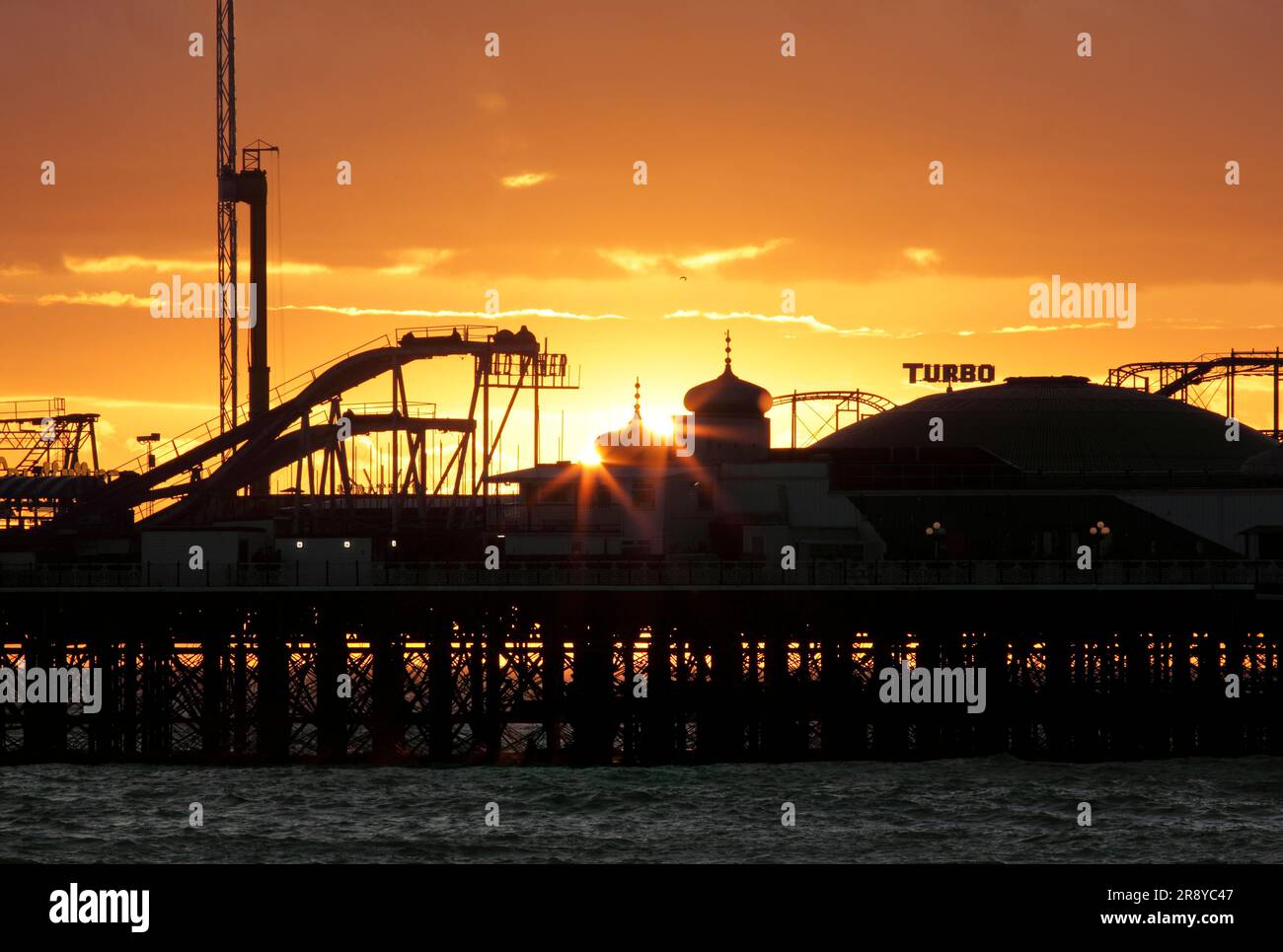 Le soir, le soleil se couche derrière deux dômes à oignons au bout de Brighton's Palace Pier. Banque D'Images