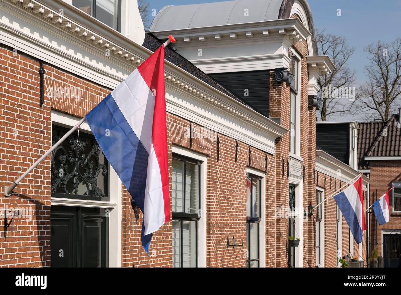 Drapeaux hollandais agitant dans une rue hollandaise sur Koningsdag sous un ciel bleu. Koningsdag est une fête nationale du Royaume des pays-Bas. Banque D'Images