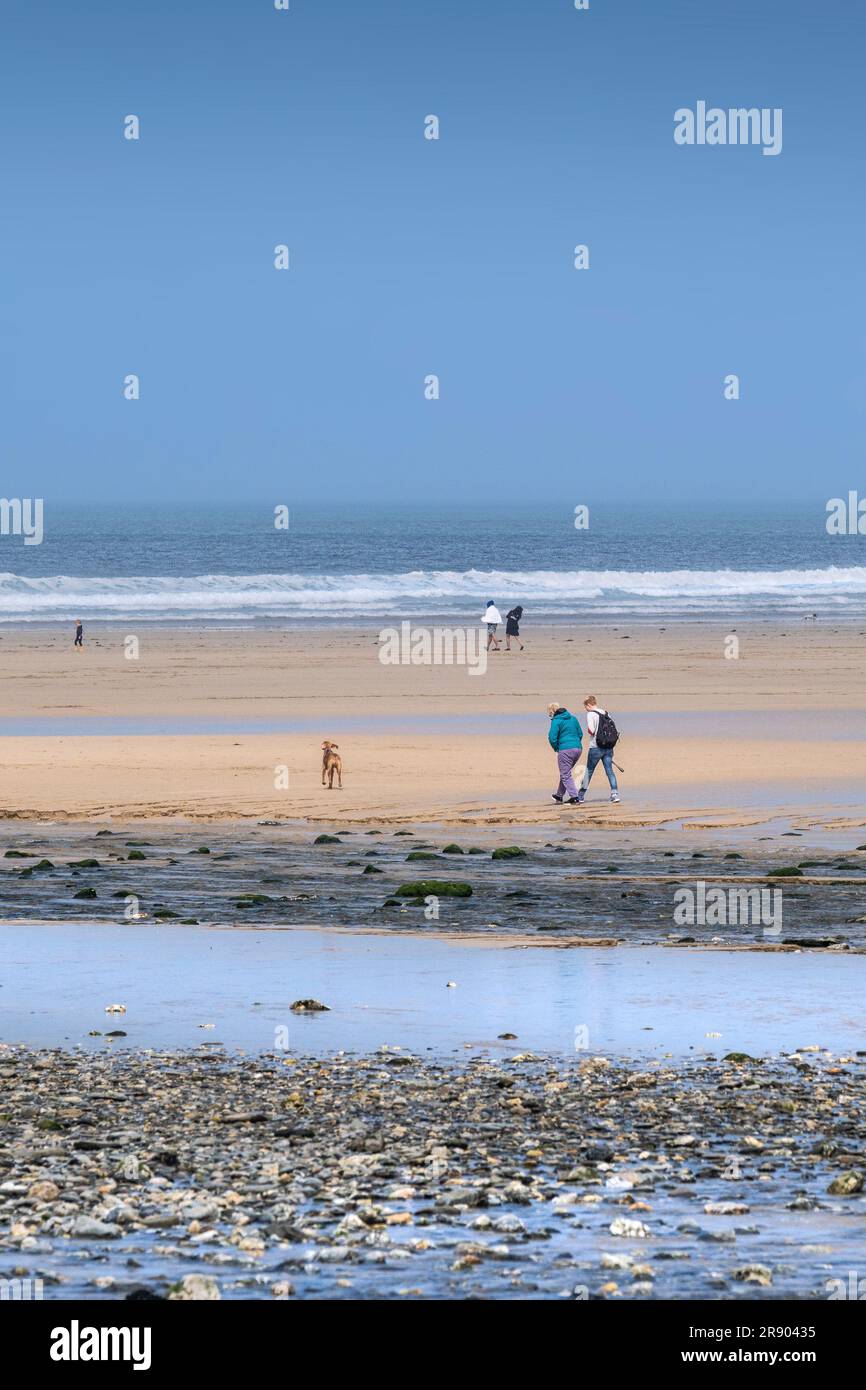 Personnes marchant sur une plage calme de Mawgan Porth à Cornwall au Royaume-Uni. Banque D'Images