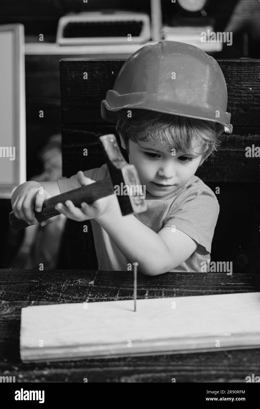 Enfant avec casque en casque orange. Construction d'outils. Un garçon martelant. Marteaux pour enfants Banque D'Images