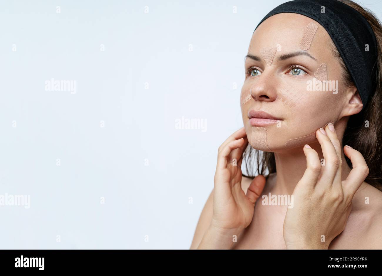 Femme modèle de beauté appliquant des bandes de kinésio du visage sur son visage, levage de la peau, soins de la peau, anti-rides. Banque D'Images
