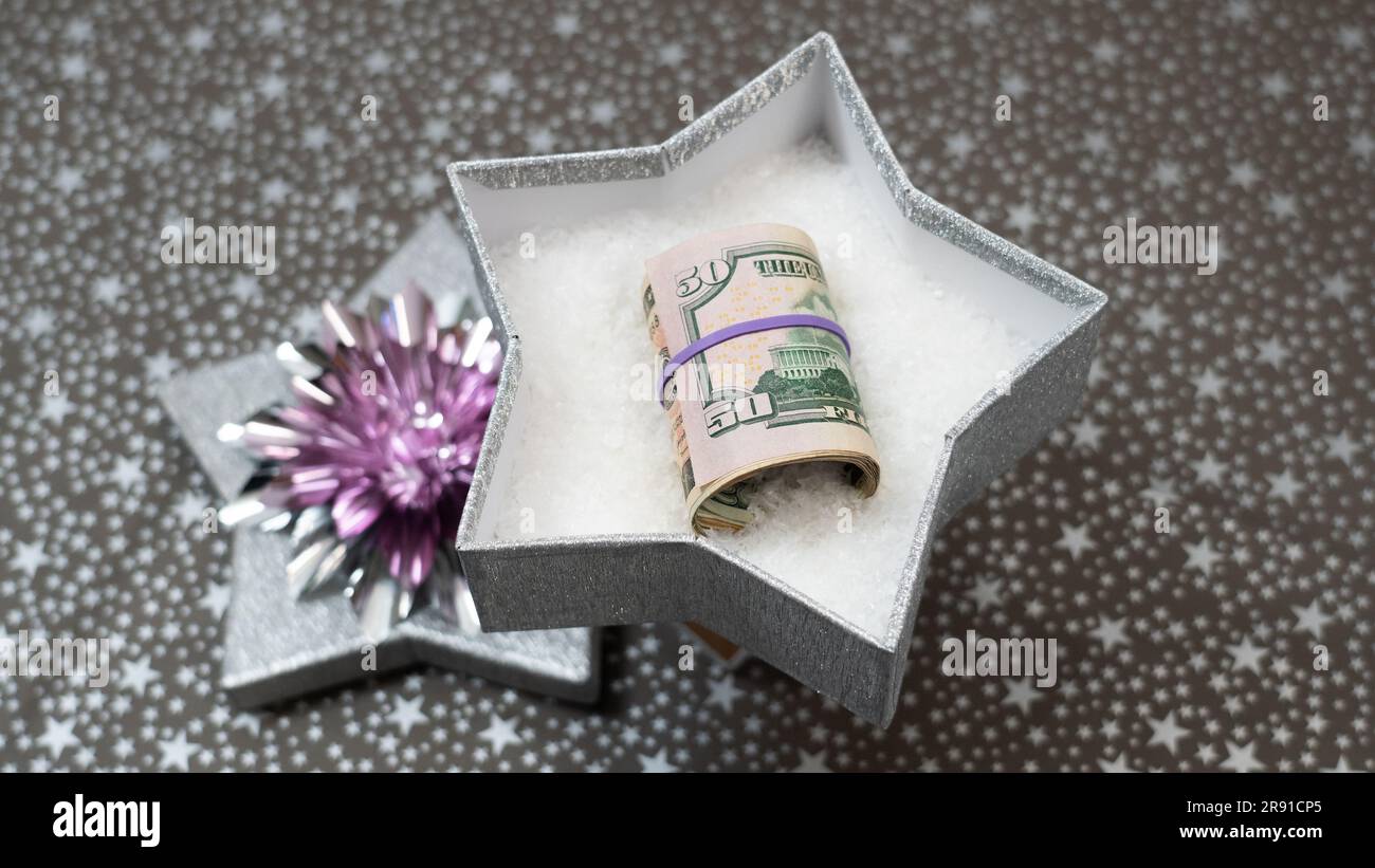Bande caoutchouc argent. Moyen de donner de l'argent comme cadeau. Donner de l'argent en cadeau. Argent de caoutchouc. Un cadeau monétaire dans une boîte argentée d'étoiles brillantes, le motif étoiles, Banque D'Images